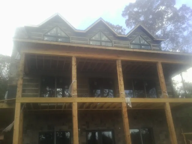 Dormers and porch framing on a large log home under construction — Roof Coating work by our crew in Glen Rock