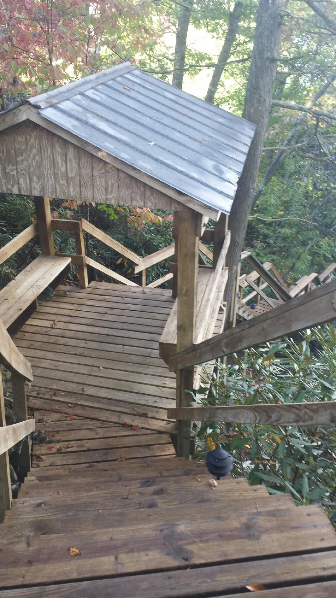 Metal roofed shelter over wooden steps on a wooded walkway — Skylight Repair & Installation work by our crew in Glen Rock