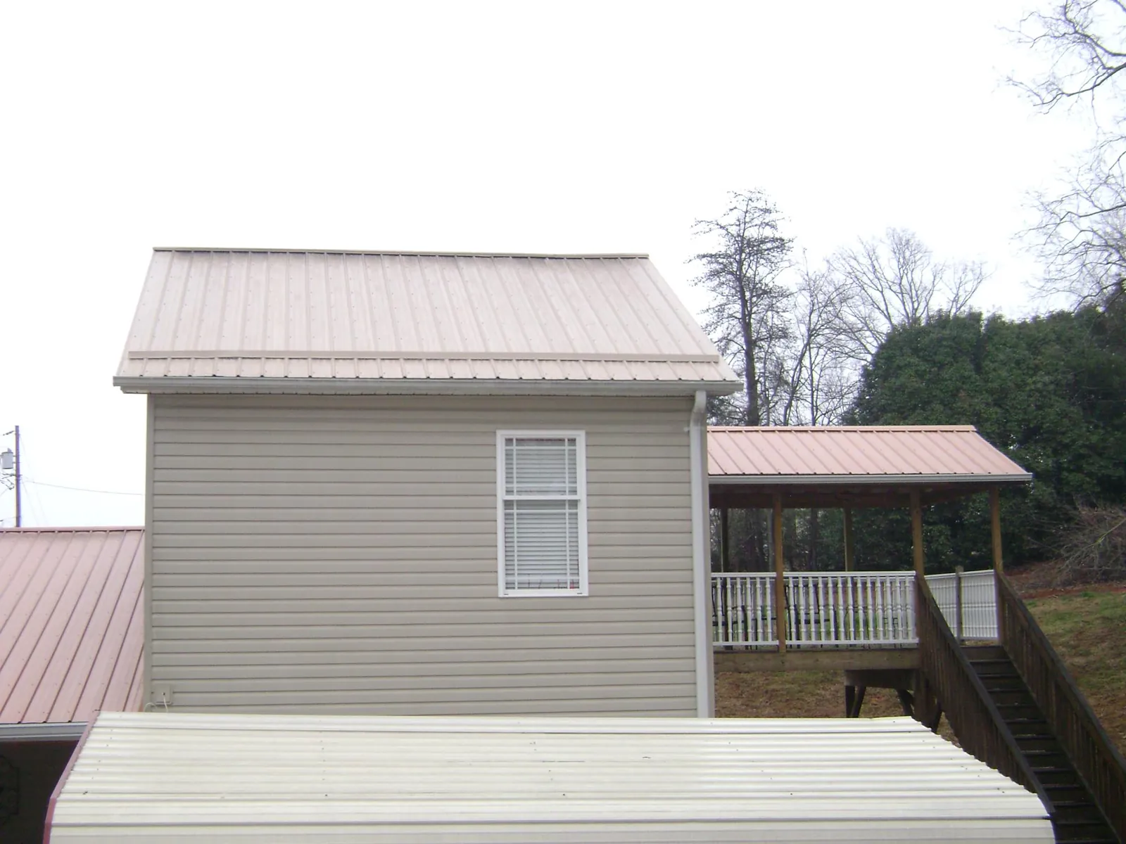 Tan metal roofs on a two story addition and attached porch, from a Roof Replacement job in Glen Rock